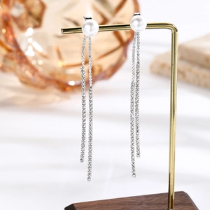 Detailed close-up of long tassel earrings with white pearls and sparkling rhinestone chains