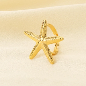 Detailed view of a gold starfish ring with an irregular textured metal finish on fabric