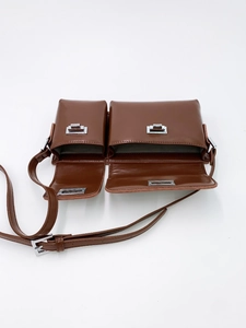 Detailed macro view of brown PU leather bag with silver metal buckle and dual compartments