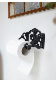 Close-up of vintage black cast iron paper towel holder with ornate scrollwork patterns