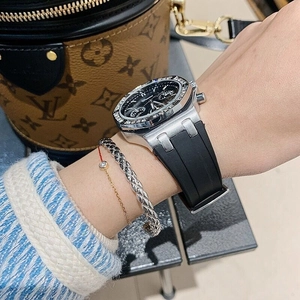 Detailed view of silver octagonal diamond bezel watch with black rubber strap on wrist