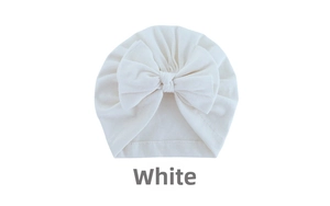 Close-up of white baby turban hat with a large bow detail made of soft knitted fabric