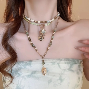 Close-up of bohemian layered necklace with beads, coins, and irregular metal pendants