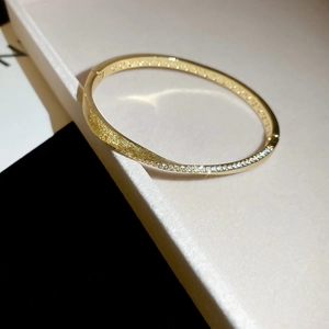 Detailed view of a gold hollow layered bracelet featuring inlaid zircons and a matte finish