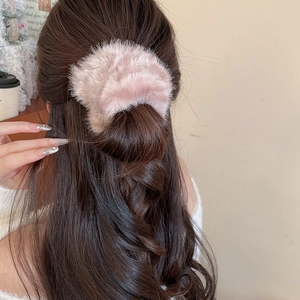 Dettaglio della pinza per capelli in peluche rosa indossata dal modello sull'acconciatura