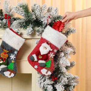 Large plush Christmas stockings with Santa and reindeer motifs hanging on a fireplace