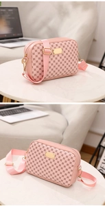 Pink crossbody bag with geometric print and gold metal plate on a marble table