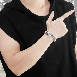 Close-up of polished thick Cuban link bracelet and textured silver ring on male model