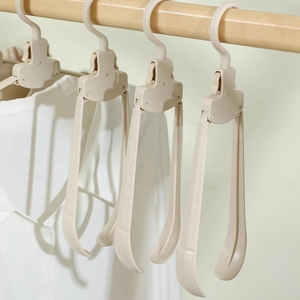 Beige portable folding clothes hangers with wide shoulders hanging on a wooden rod