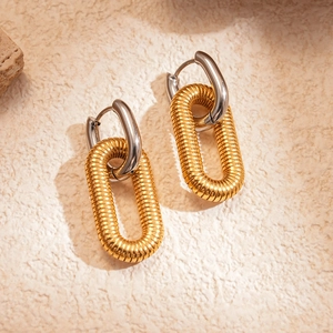 Detail of two-tone gold and silver U-shaped earrings with textured oval link on stone