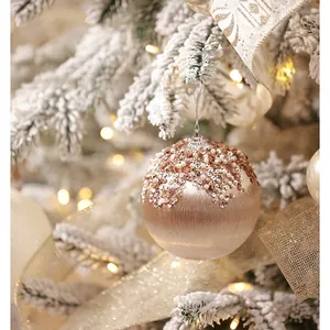 Champagne gold Christmas ball ornament with sequins and pearls on snowy pine branch