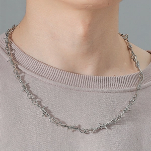 Close-up of a silver thorn barbed wire necklace styled on a fashion model's neck