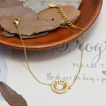 Detail of a gold plated twist chain necklace with sunburst pendant on wood texture