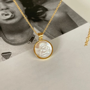 925 sterling silver gold-plated cherub necklace with white shell pendant on art magazine