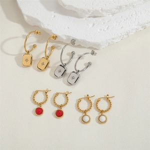 Detail of hexagram and turquoise charms on gold stainless steel twist hoop earrings