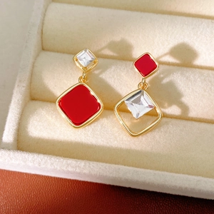 Detail of 18k gold plated rhombus earrings featuring red enamel and zircon stones