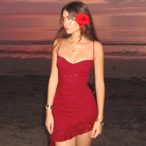 Detail of red sequin dress with ruffled hem and slim fit design at sunset beach