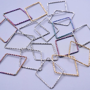 Macro view of textured geometric diamond pendants in gold silver and rainbow finishes