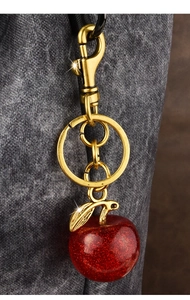 Close-up of a red glitter apple-shaped keychain charm with elegant golden metal ring and clasp