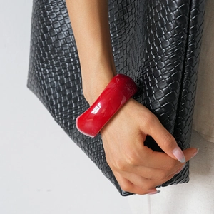 Close-up of a wide red acrylic cuff bracelet on wrist with high-gloss finish