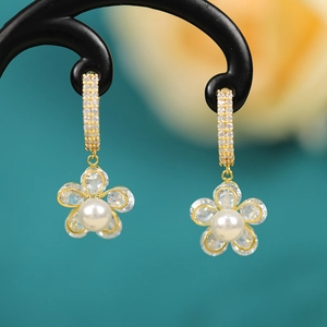 Macro detail of elegant flower drop earrings with crystal petals and pearl centers