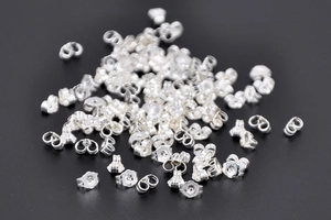 Close-up of silver butterfly earring backs in bulk made of polished metal material