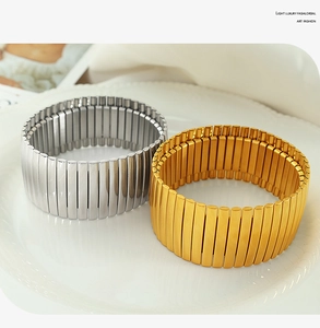 Detailaufnahme von dehnbaren Gold- und Silberarmbändern mit Karomuster auf einem Teller