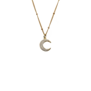 Golden crescent moon pendant necklace with zircons and beaded chain on white background