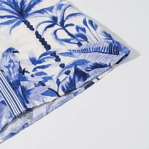 Detail of tropical island print fabric with blue palm trees and parrots on linen texture