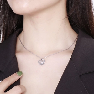 Close-up of double hollow heart pendant necklace worn on model neck in silver finish