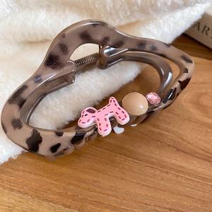 Detail shot of leopard print claw clip with pink cartoon dog pendant and small rhinestones