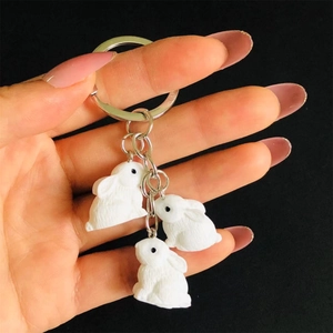 Handheld three white cartoon rabbits keychain with textured resin charms on metal rings