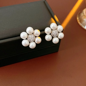 Close-up of pearl flower earrings with sparkling cubic zirconia on a black jewelry box