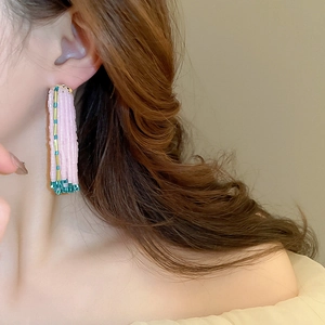Close-up of pink and green beaded tassel earrings worn by a model in a boho style