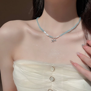 Détail du collier de perles bleu clair avec pendentif étoile de mer et charms poissons
