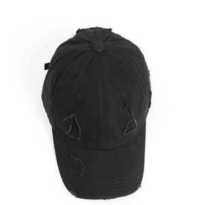 Close-up of distressed black cotton baseball cap showing ripped details and vintage texture