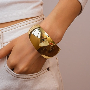 Close-up of a wide polished gold irregular cuff bracelet worn by a model in a minimal style