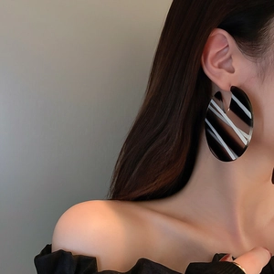 Close-up of model wearing oversized black and white striped acrylic hoop earrings
