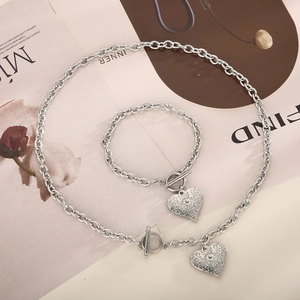 Detail of silver chain jewelry set with embossed heart pendant and OT buckle design