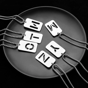 Brushed silver stainless steel alphabet necklaces on black tray with ball chain link