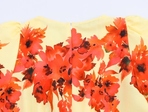 Nahaufnahme der gelben Kleid-Rückseite mit Blumenmuster, Reißverschluss und Puffärmeln