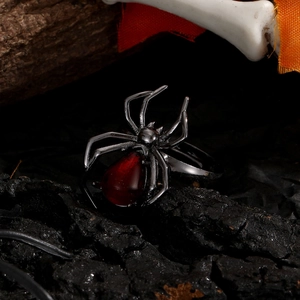 Macro d'une bague araignée gothique avec pierre rouge goutte sur une roche sombre