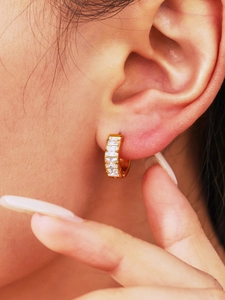 Macro shot of gold hoop earring with five vertical rectangular cubic zirconia stones