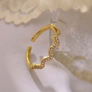 Detail of wave-shaped 18K gold-plated ring with shimmering pink zircons on lace fabric