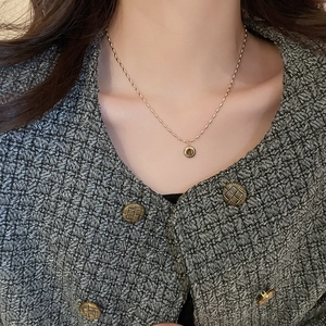 Detailed view of a gold tiger eye pendant necklace styled with a gray tweed jacket