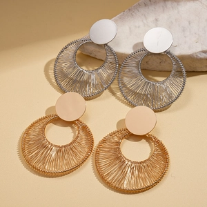 Modern hollow circular metal earrings in gold and silver finishes on a textured stone base