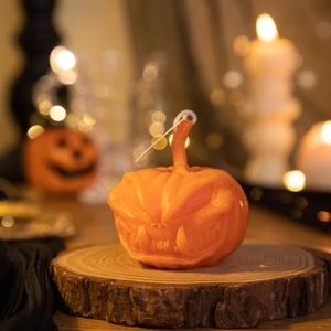 Detailed close-up of an orange pumpkin-shaped scented candle on a rustic wood base