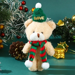 Close-up of beige plush teddy bear wearing green knitted hat and red-green scarf