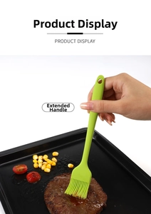 Close-up of green silicone oil brush with long handle applying sauce on a grilled steak