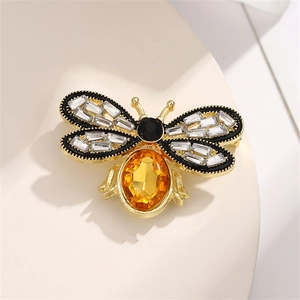 Macro detail of a crystal bee brooch with golden wings and a large yellow gemstone